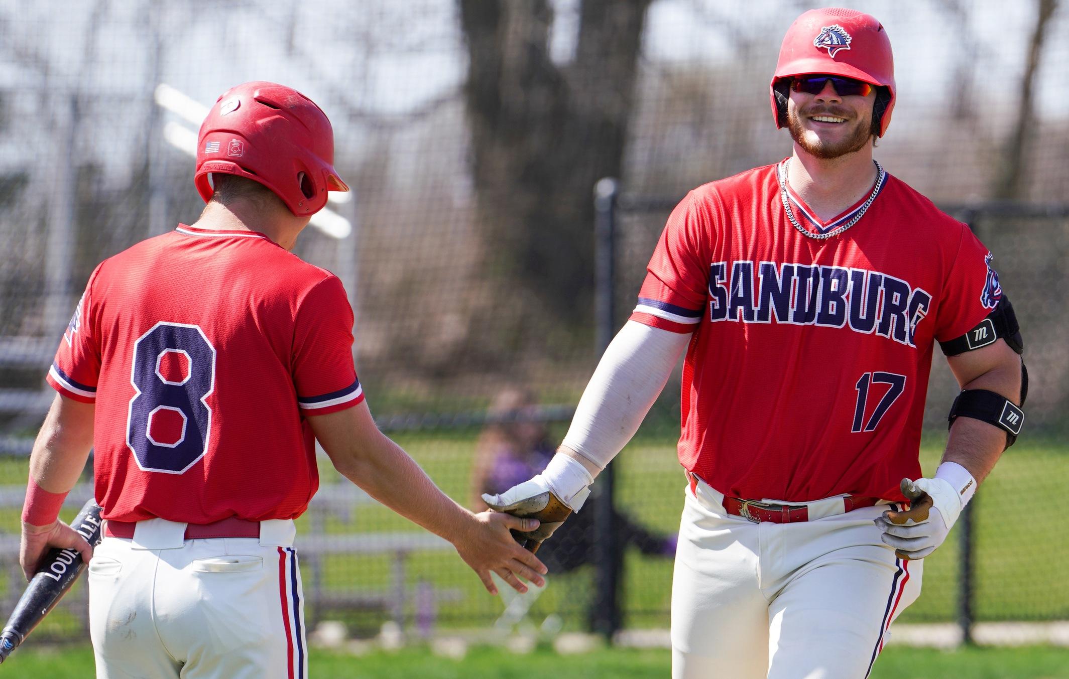 Chargers freshman Frank Kelch high-fives teammate Logan Van Heuklon after scoring a run against Illinois Valley.